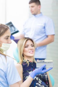 Dental professional showing tooth shade guide to patient during whitening consultation at Sweet Hart Dental.