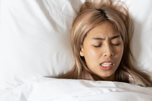 woman grinding teeth in her sleep, bruxism