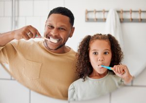 child and dad brushing teeth