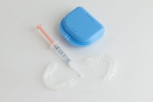 Take-home teeth whitening kit with custom trays, syringe of whitening gel, and blue storage case, illustrating professional dental whitening options available at Sweet Hart Dental.
